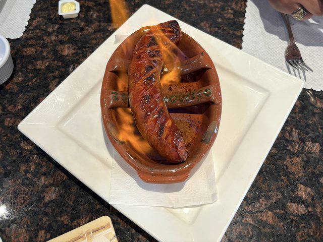 Chouriço Assado flaming in a traditional clay dish